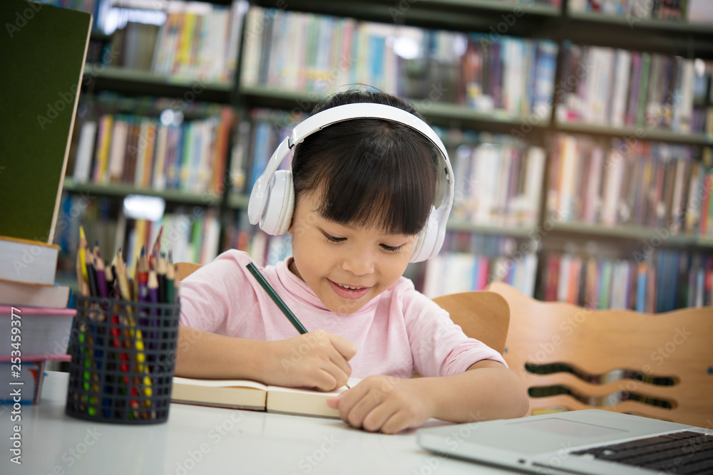 Cute asian little girl reading a book and headphones listening to music, Cute asian little girl reading a book and headphones listening to music,