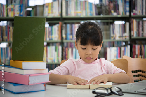 Cute asian little girl reading a book.Concept of education and reading