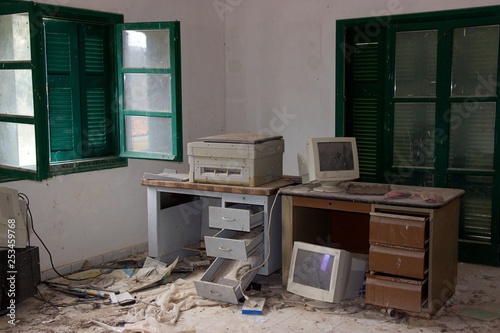 Grunge old abandoned office with drawers desks monitors and computers photo