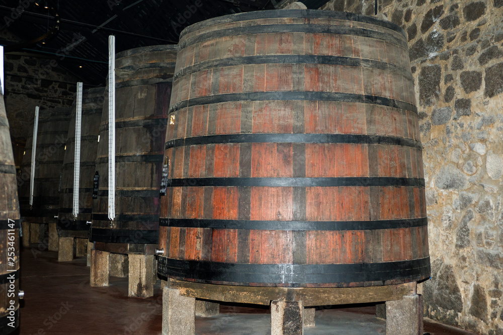 Huge vertical barrels of port. Dimensional levels are set along the barrels. The barrels are standing on stone pedestals.