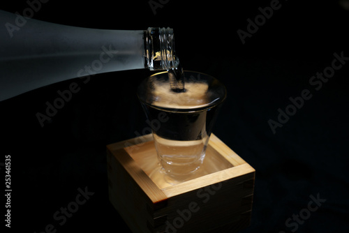 Tokyo,Japan-March 7, 2019: Pouring sake into a glass inside a wooden container for drinking or measuring sake