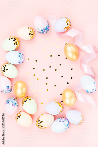 Festive Happy Easter background with decorated eggs, flowers, candy and ribbons in pastel colors on pink. Copy space