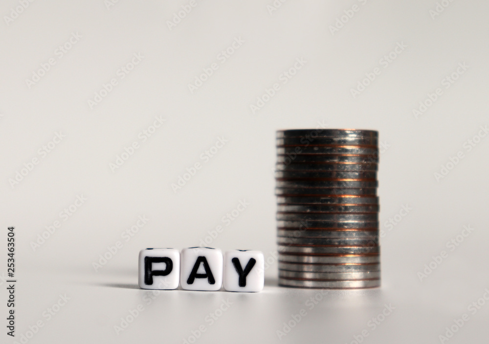 ‘PAY' text in white cube and a pile of coins. ‘PAY' text in white cube and a pile of coins.