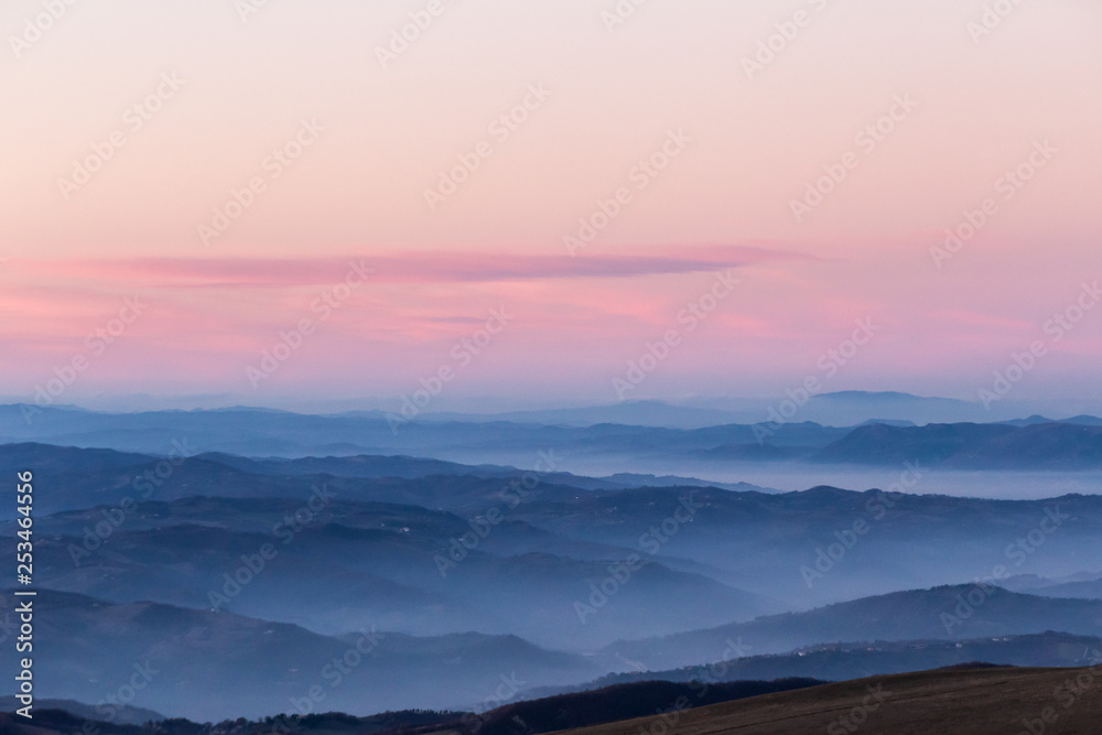 Beautifully colored sky at dusk, with mountains layers and mist between them