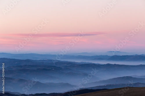 Beautifully colored sky at dusk  with mountains layers and mist between them