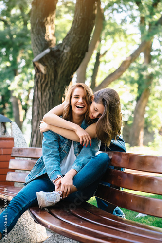 Two beautiful young woman resting on a bench