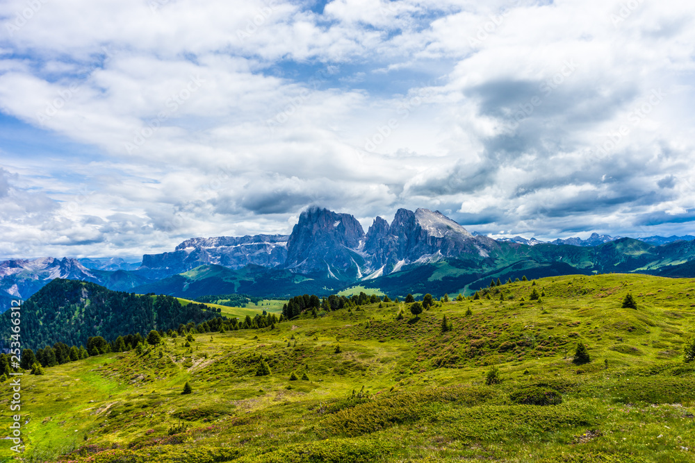 Alpe di Siusi, Seiser Alm with Sassolungo Langkofel Dolomite, a large green field with a mountain in the background Alpe di Siusi, Seiser Alm with Sassolungo Langkofel Dolomite, a large green field with a mountain in the background