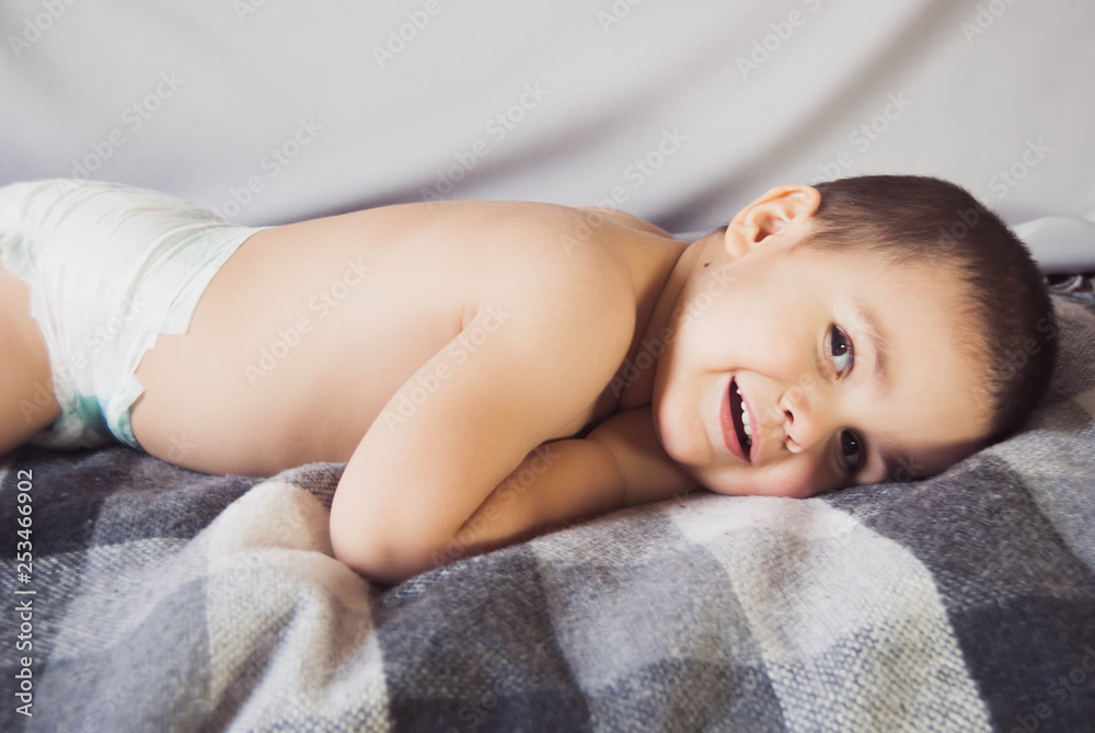 three year old cute boy lying on the bed and smiling