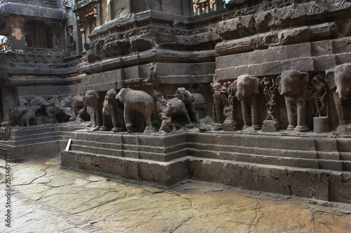 ELLORA, AURANGABAD, MAHARASHTRA, October 2018, Tourist at Cave 16 with huge beasts carved around the shrine's high plinth or platform including elephants, leonine and other bestial forms. photo