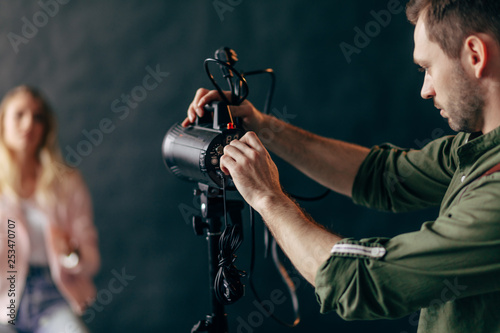 young handsome man working with a professional studio strobe photo flash light.close up photo. blurred background