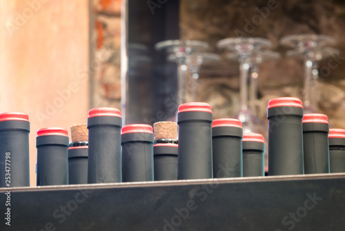 Fotografie Italian wine bottle necks with defocused glasses in background