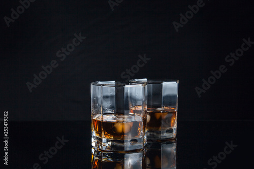 Two glasses of whiskey with ice isolated on black background..