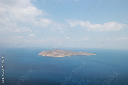 A small island in the sea with blue water off the coast of Crete