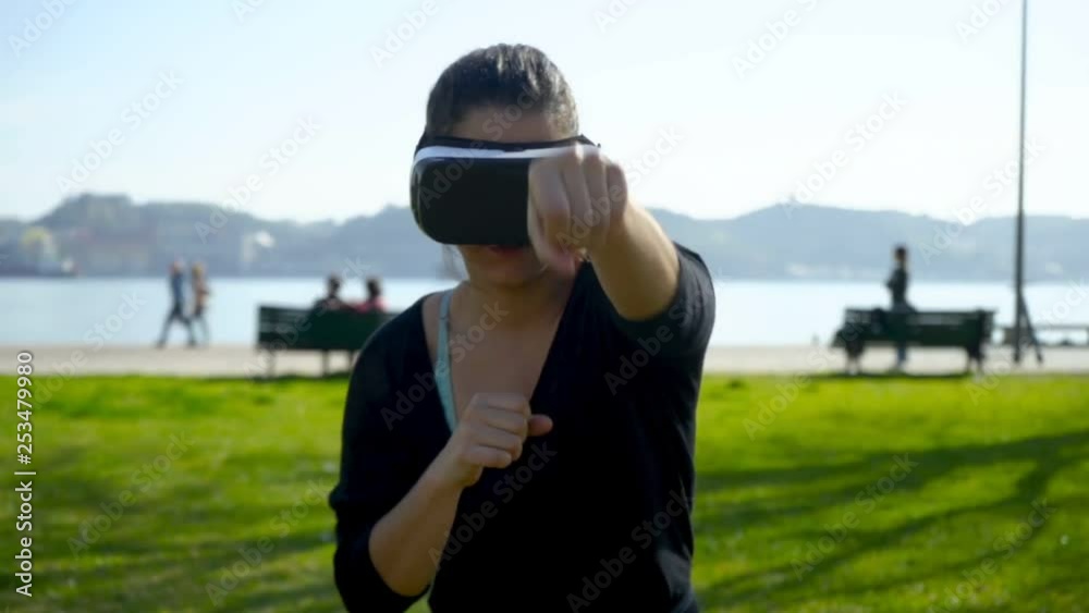 Athletic woman in vr headset boxing outdoor. Young woman in sportswear using virtual reality headset during workout in park, slider shot. Technology concept Athletic woman in vr headset boxing outdoor. Young woman in sportswear using virtual reality headset during workout in park, slider shot. Technology concept