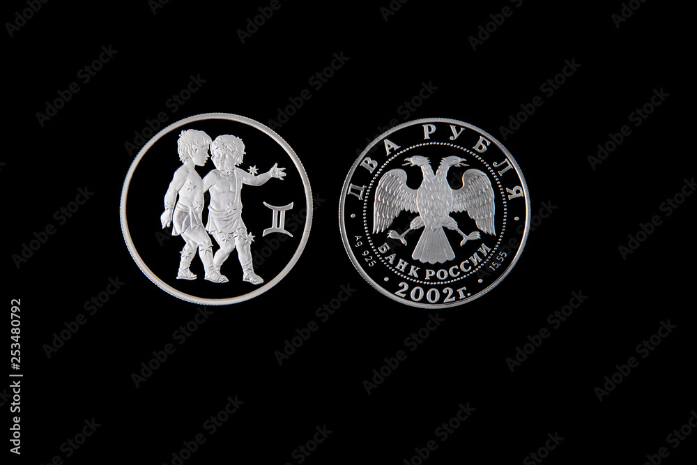 Fototapeta premium Silver coin of the Bank of Russia with the sign of the zodiac Gemini on a black isolated background. The coin says: 