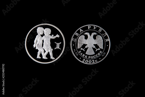 Silver coin of the Bank of Russia with the sign of the zodiac Gemini on a black isolated background. The coin says: "Two rubles. Bank of Russia".