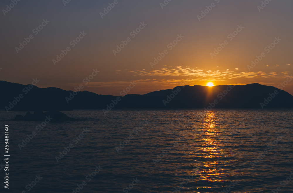 Dramatic Sunset over Mountain silhouettes under red sky and blue Sea on fethiye Mediterranean Turkey