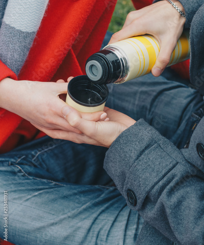 couple in love drinking coffee, tea from a thermos in the park