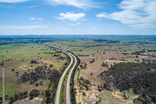 Hume Highway winding through meadows and pastures on bright sunny day. Cullerin, New South Wales, Australia photo