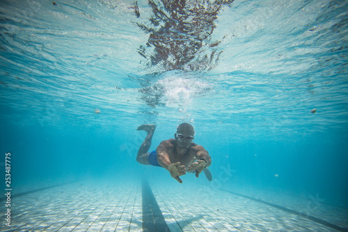 Underwater image of a male swimmer diving and swimming in a swimming pool to train