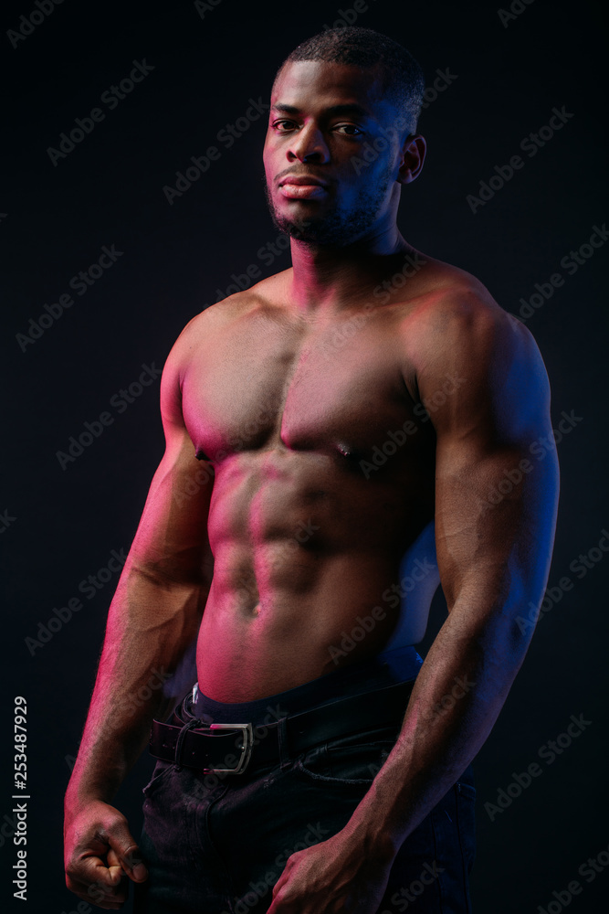 Muscular man African bodybuilder. Man posing on a black background, shows his health and perfect shape.
