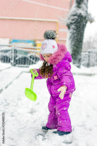 Little kid girl shoveling s...