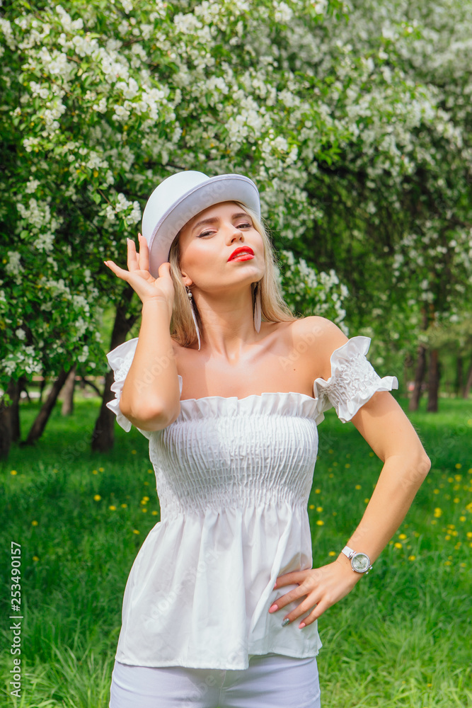 Sexy modern bride in white cylinder hat enjoing bloomin apple tree flowers. Sexy modern bride in white cylinder hat enjoing bloomin apple tree flowers.
