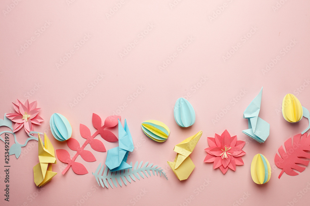Easter papercraft background, various eggs end bunny and origami paper floral flowers on pink background, flat lay, view from above, blank space for greeting text