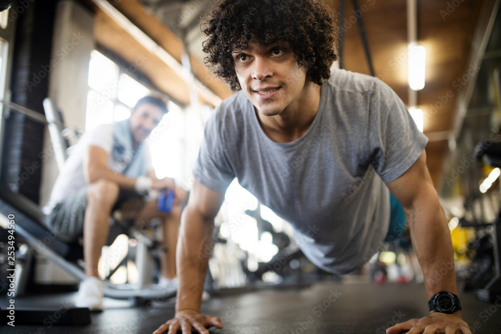 Handsome happy fit man doing exercises in gym