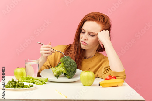 Fotografie Sad red-haired woman in bad temper keeping strict vegetarian diet being tired of restrictions and hates greenery