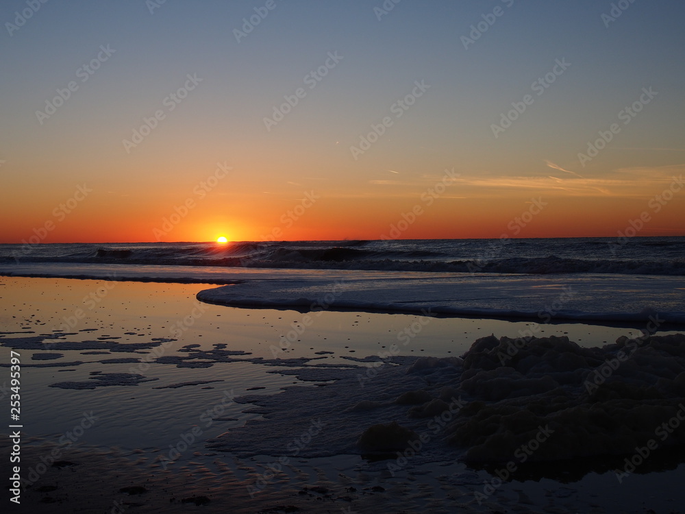 sunset at a beach (north sea, north netherland) , foam of sea water 
