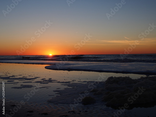 sunset at a beach  north sea  north netherland    foam of sea water 