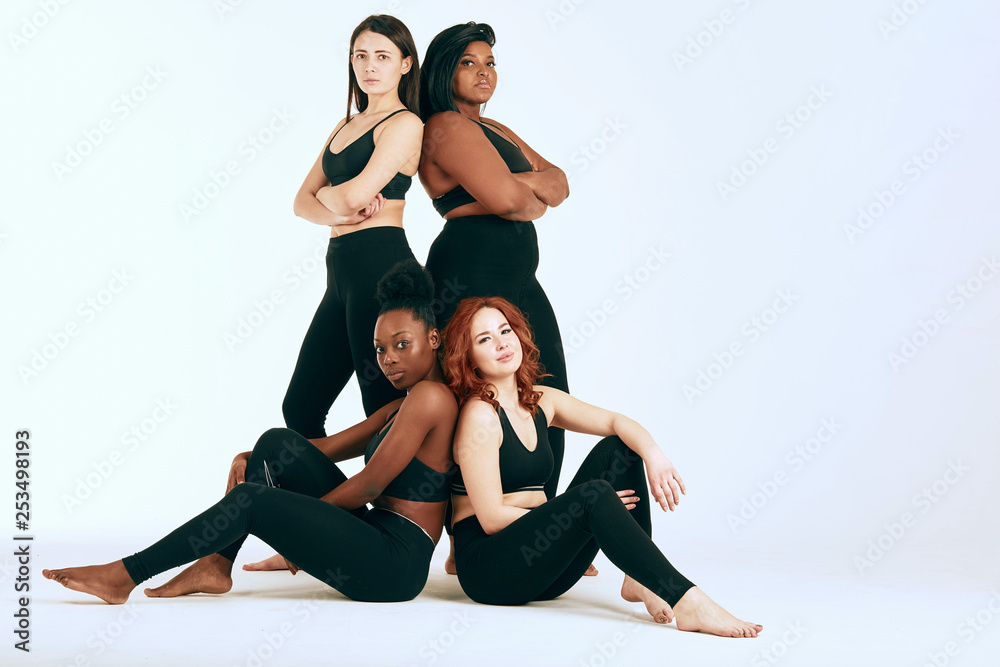 Two multiracial lesbian couple of different body size in sportswear looking at camera with glad, satisfied expression being happy on workout together. Two multiracial lesbian couple of different body size in sportswear looking at camera with glad, satisfied expression being happy on workout together.