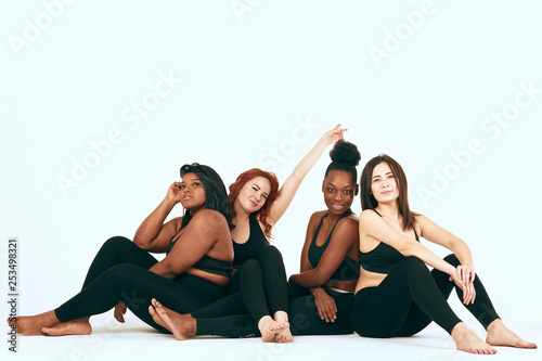 Four multiracial diverse woman in sportswear sitting on the floor and discussing the specificities of woman s training depending on type of figure