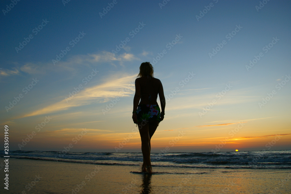 walking woman silhouette. women walking on California beach against a colorful sunset