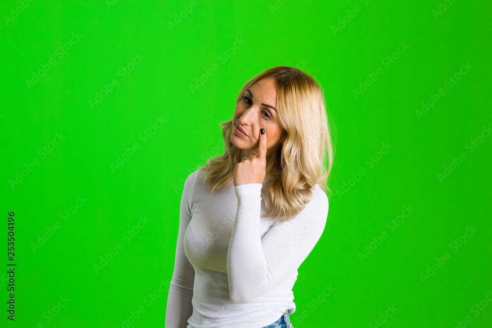 Positive attractive young female, points aside with cheerful expression, shows something amazing at blank space Positive attractive young female, points aside with cheerful expression, shows something amazing at blank space