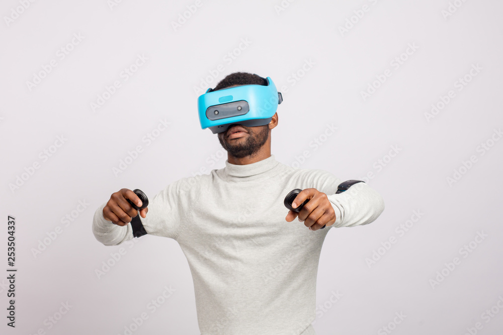 Stylishly dressed african guy using new VR technology headset, learning material and getting knowledge and practice through 3D video glasses. Virtual education concept
