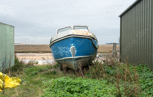 Old boat pulled on to dry land for repairs photo