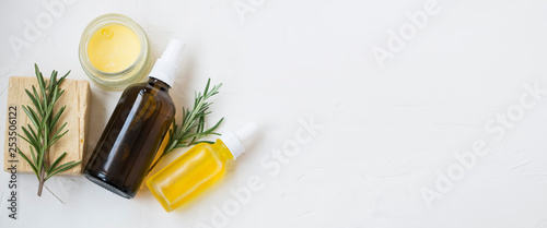 Natural skincare ingredients with floral water bottle  essential oil bottle  rosemary herb  balm and natural soap with copy space top view  natural organic skincare still life