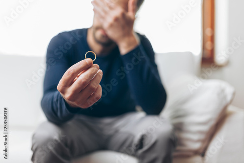 Heartbroken man holding a wedding ring photo