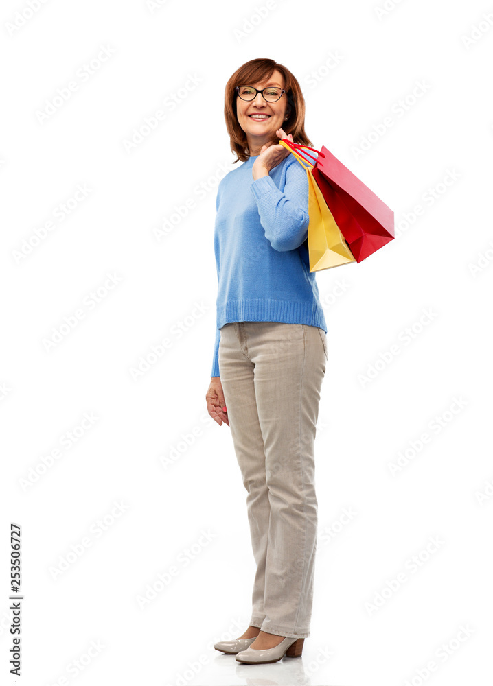 sale and old people concept - smiling senior woman in glasses with shopping bags over white background