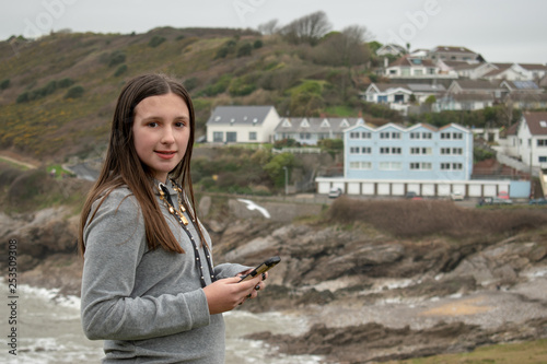 Girl with phone with Limeslade bay, Swansea as a background