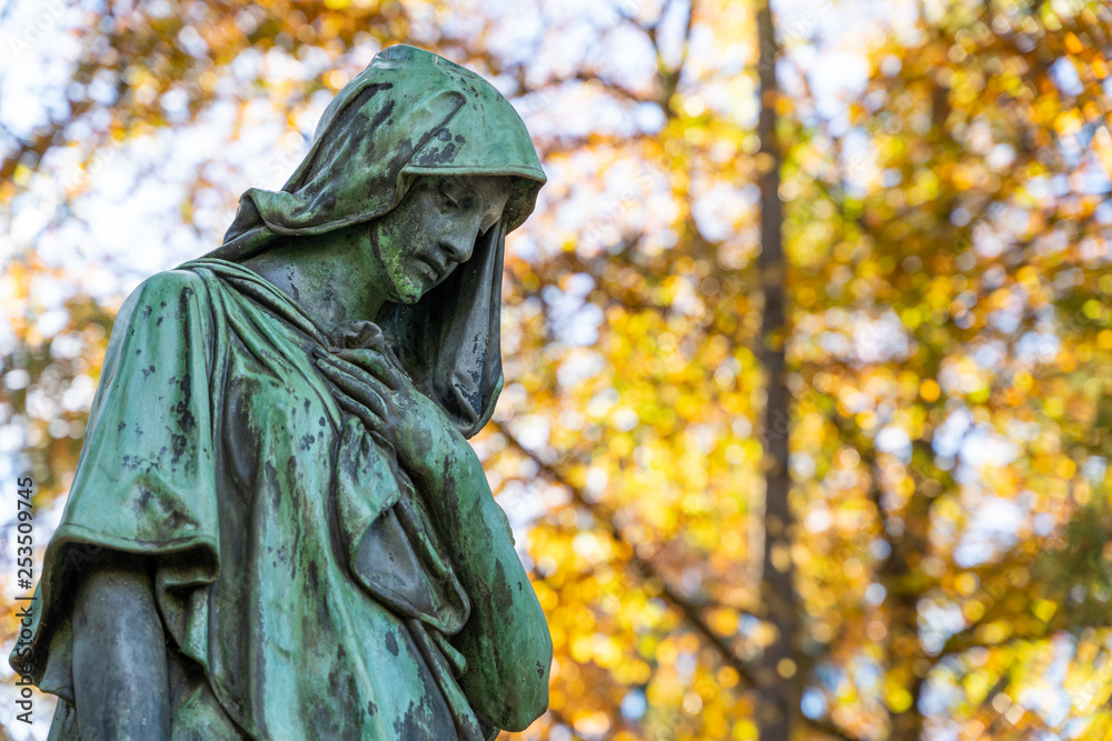 Trauernde Figur im Herbst auf Friedhof