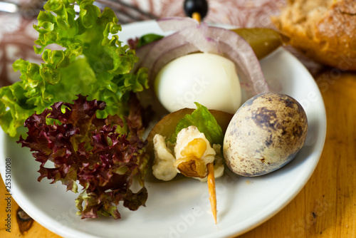 Plate with lettuce, quail egg, nut and cheese.
