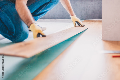 The builder is engaged in laying laminate in the room - repair and finishing work