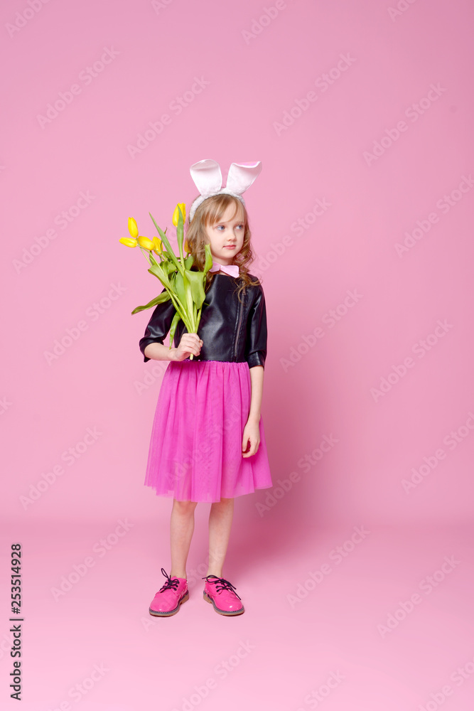 Funny girl in the shape of an Easter Bunny with a bouquet of yellow tulips. Concept of holidays, beauty and fashion. Selective focus.