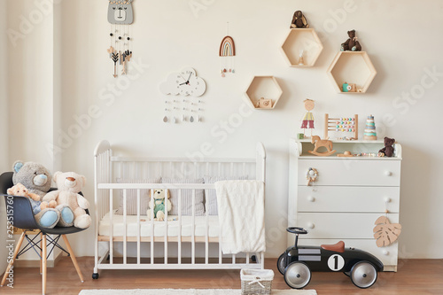 wooden toys in the children's room, chest of drawers and a white bed, the interior of the children's bedroom photo