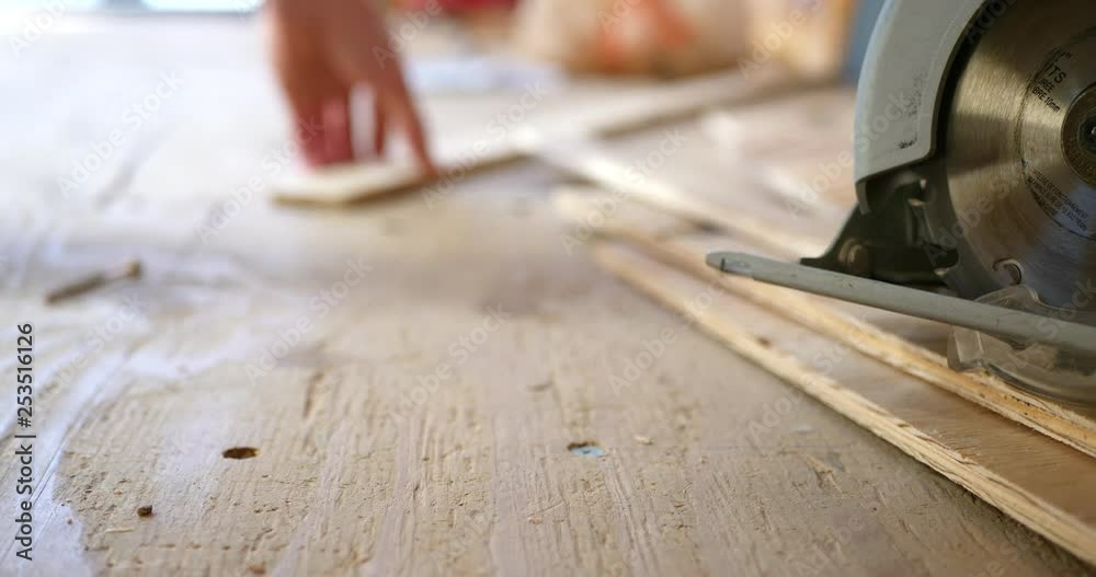 A power tool circular saw on a stack of plywood boards as workers build a new home on a construction site. A power tool circular saw on a stack of plywood boards as workers build a new home on a construction site.
