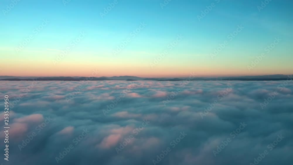 Aerial pilots view flying over fluffy clouds illuminated by a sunset, with a descend through the clouds. Aerial pilots view flying over fluffy clouds illuminated by a sunset, with a descend through the clouds.