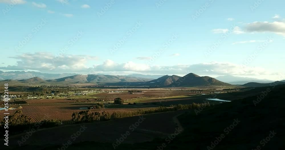 View overlooking a rural village and farmland in South Africa with mountains in the background slow pan left View overlooking a rural village and farmland in South Africa with mountains in the background slow pan left